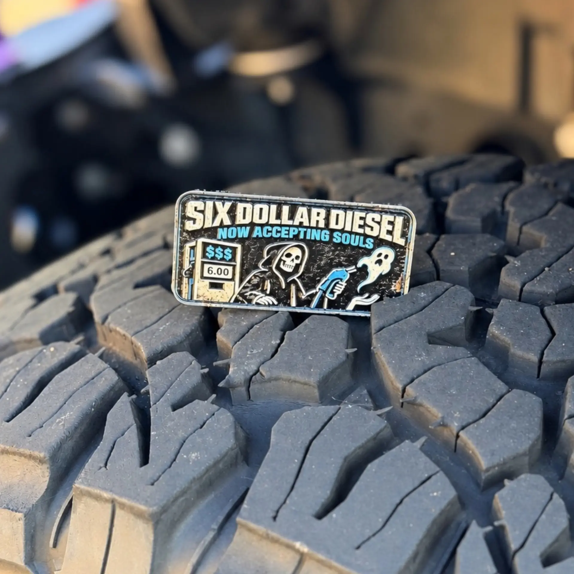Six Dollar Diesel trail badge photographed on a tire