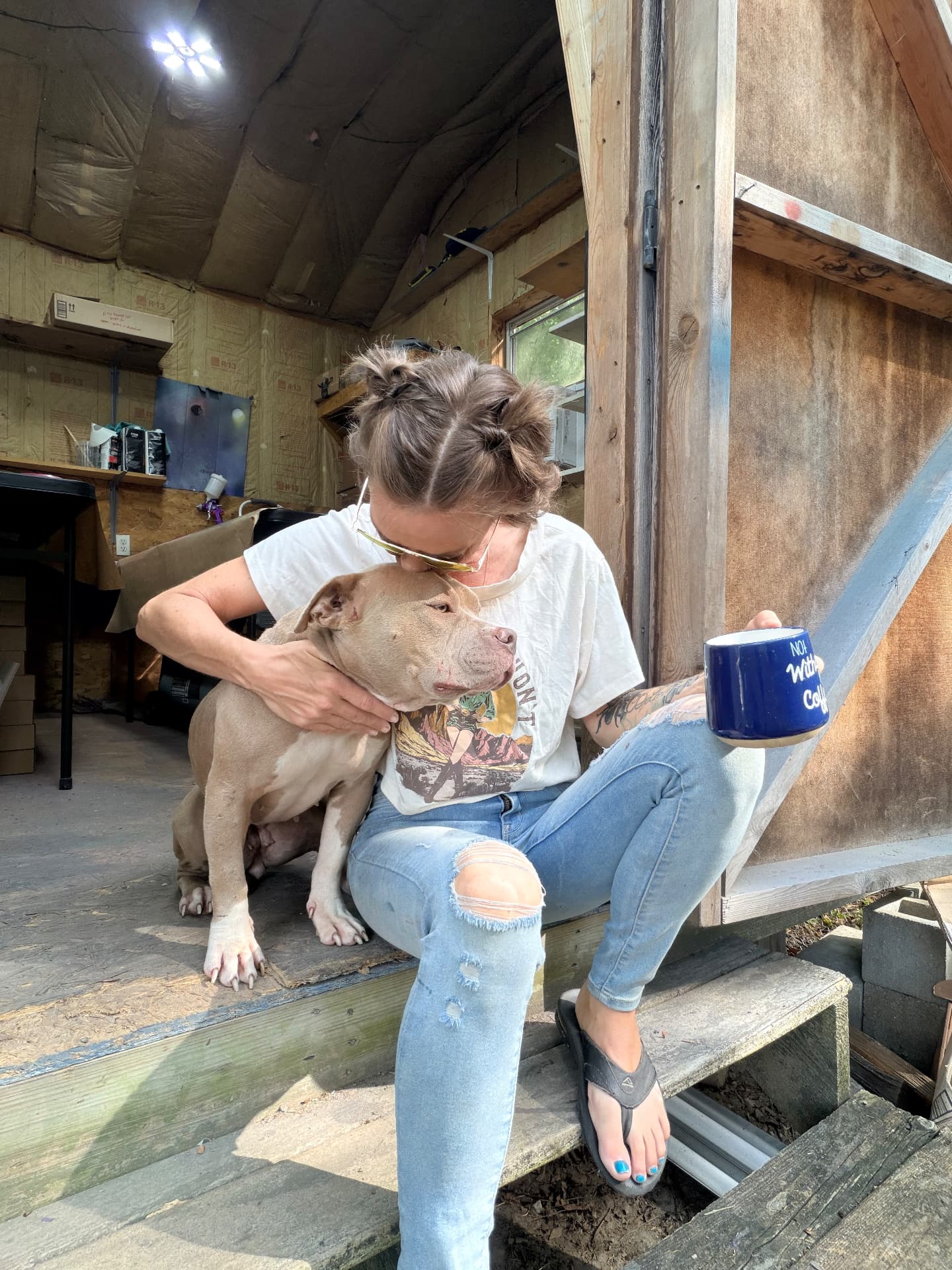 Melinda and the shop dog outside the paint booth