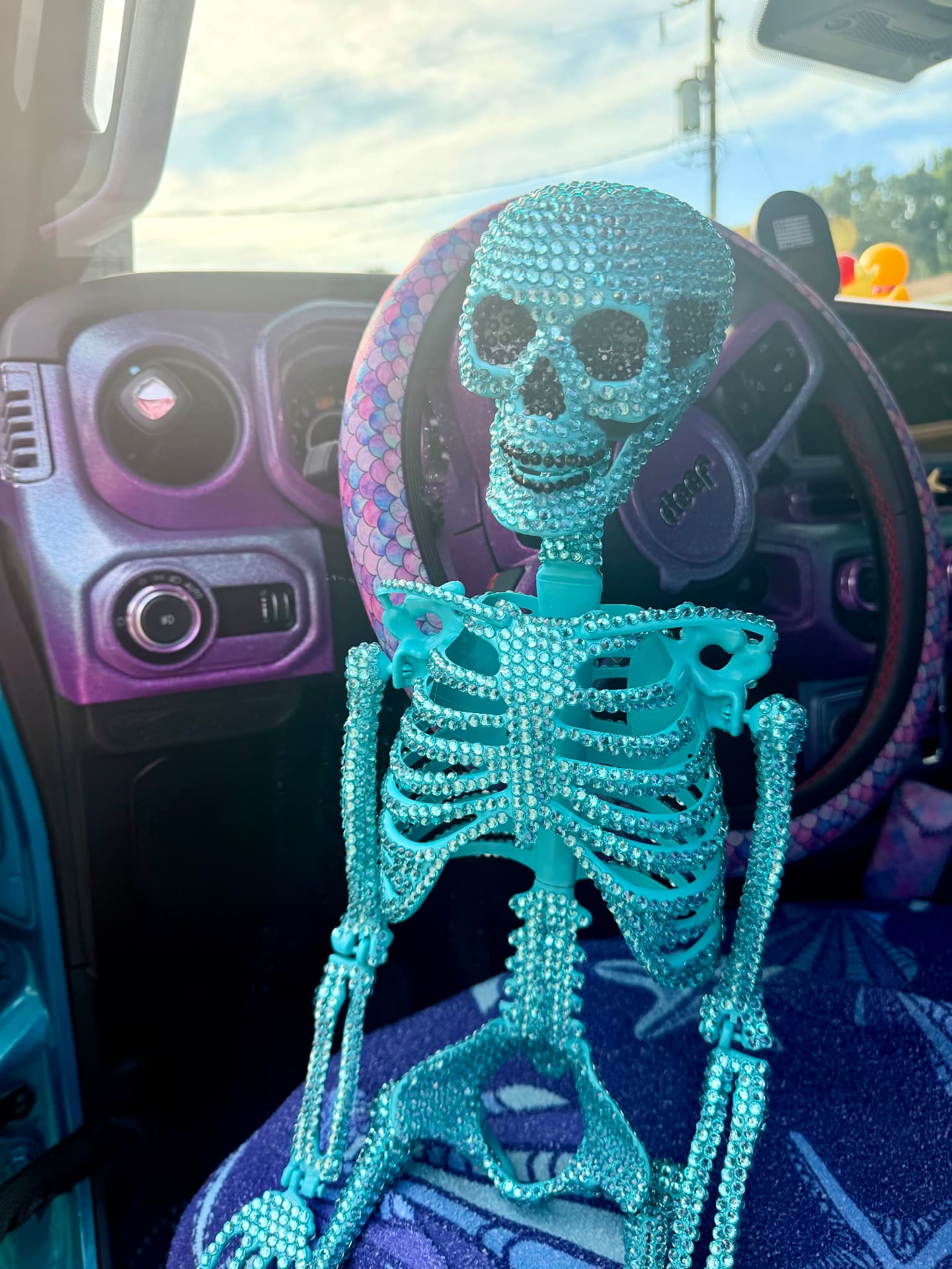 Teal rhinestone skeleton riding shotgun in a Jeep