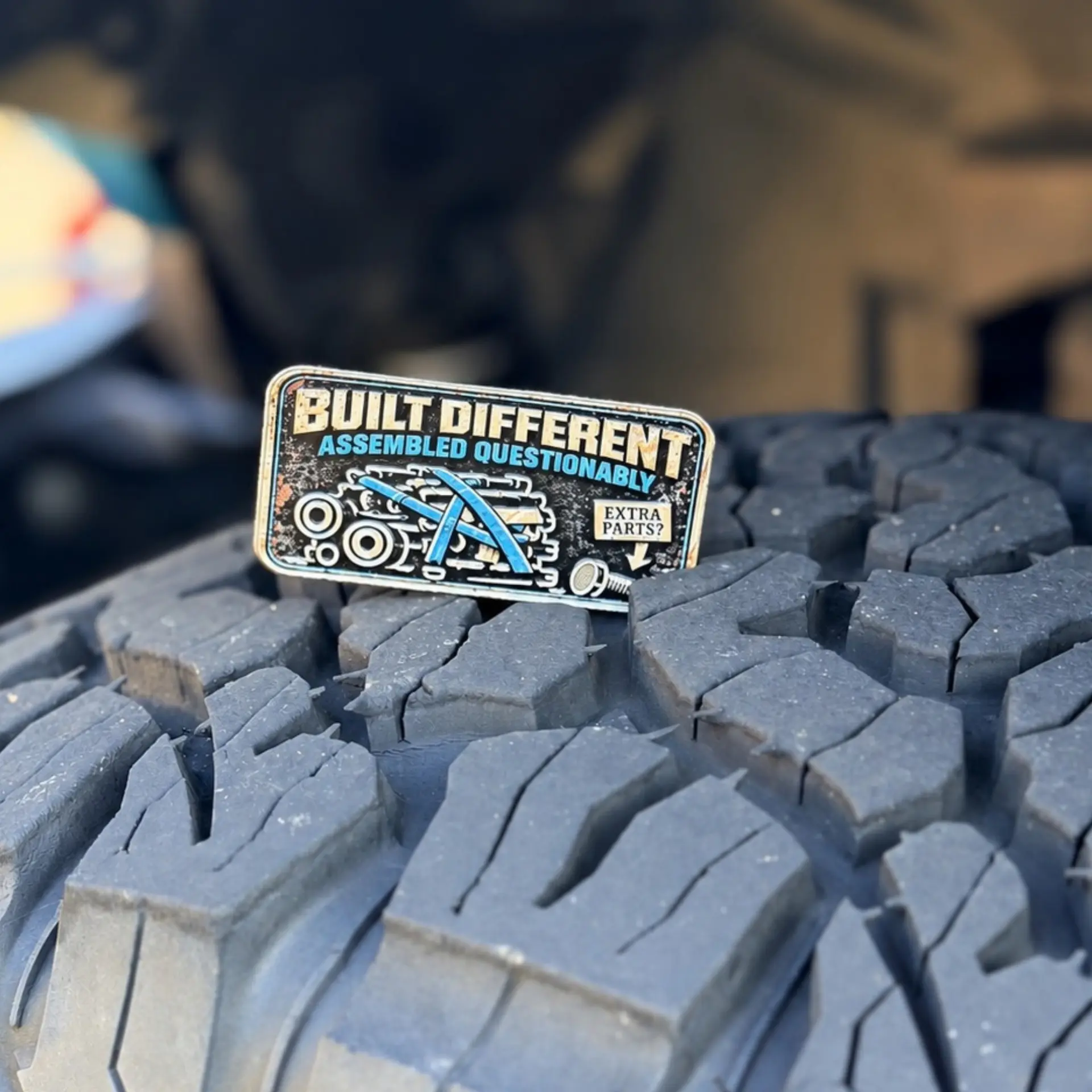 Built Different trail badge photographed on a tire